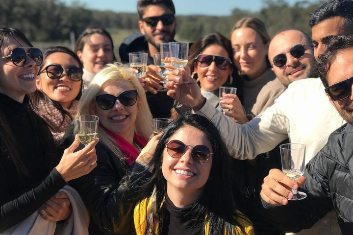 Group of people smiling and holding glasses in an outdoor setting.