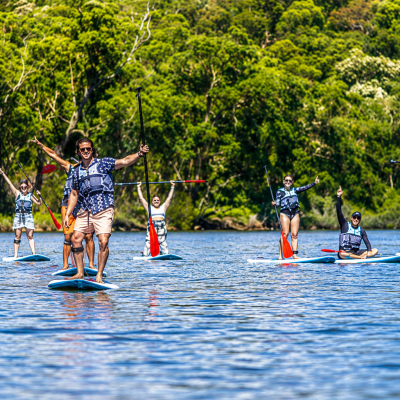 Group paddleboarding on a lake with lush green trees in the background.