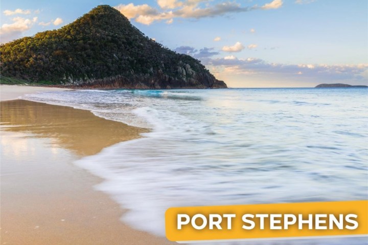 Beach with gentle waves, green hill in the distance, clear sky, and text 'Port Stephens 1 Day Tour' on image.