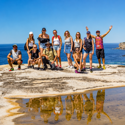 Group of people on a cliff with ocean view and blue sky.