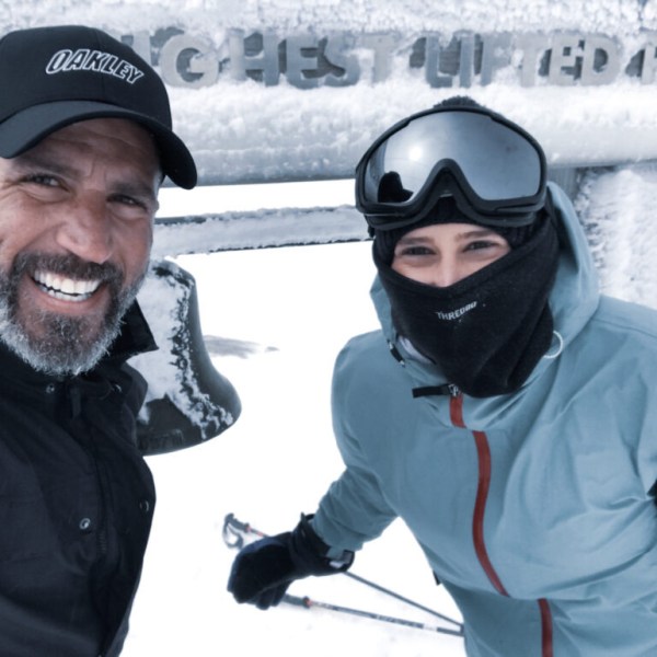 Two people in winter gear smiling in a snowy landscape.