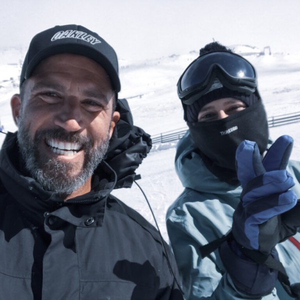 Two people in winter gear smiling on a snowy landscape.