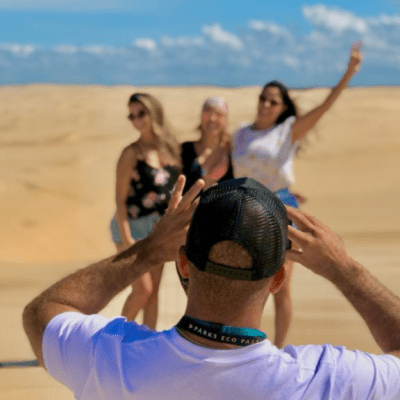 Person taking photo of three people posing in a desert landscape.