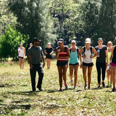 Group of people walking on a forest trail under sunlight.