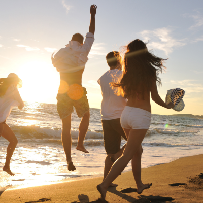 Group of people joyfully running on the beach at sunset.