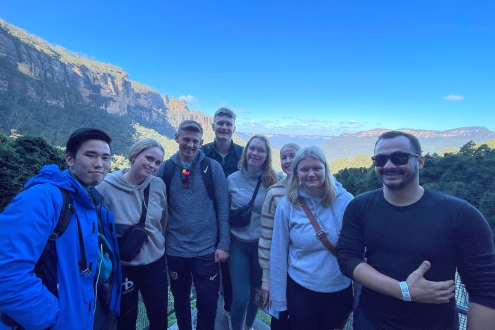 Group of people posing in front of a scenic mountain backdrop.