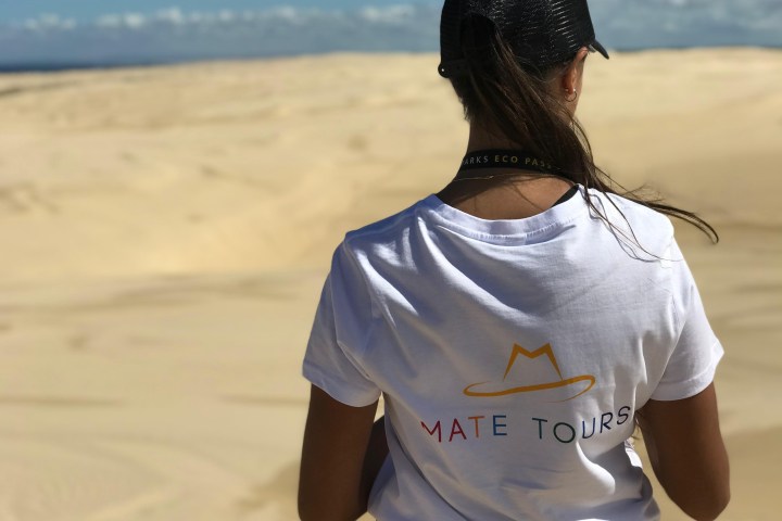 Person in white shirt and cap standing in desert landscape.