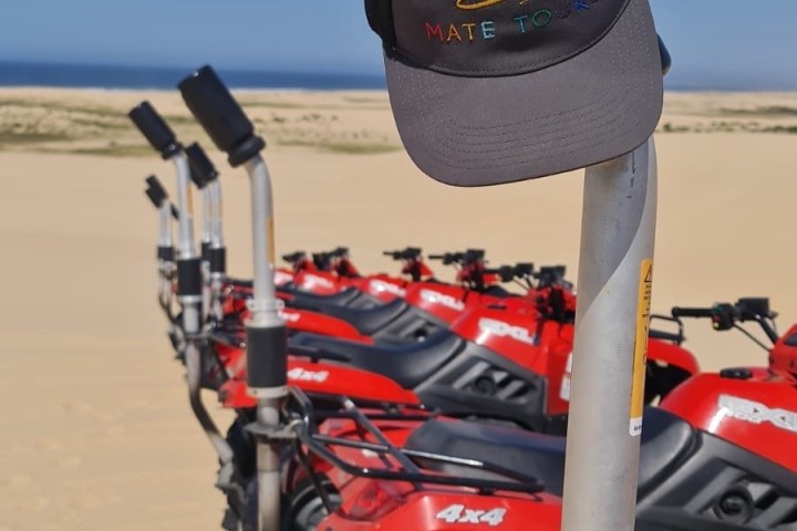 Line of parked red ATVs in desert with a branded cap on a handlebar.
